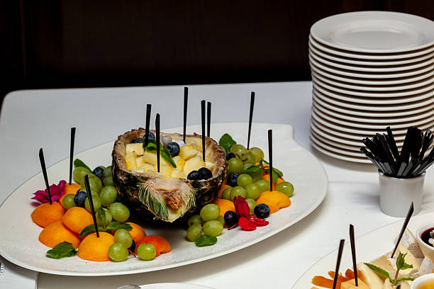 Assorted cheese cubes, dried fruits, and sauces beautifully arranged on white platters with decorative flowers, surrounded by plates and cutlery on white tablecloth