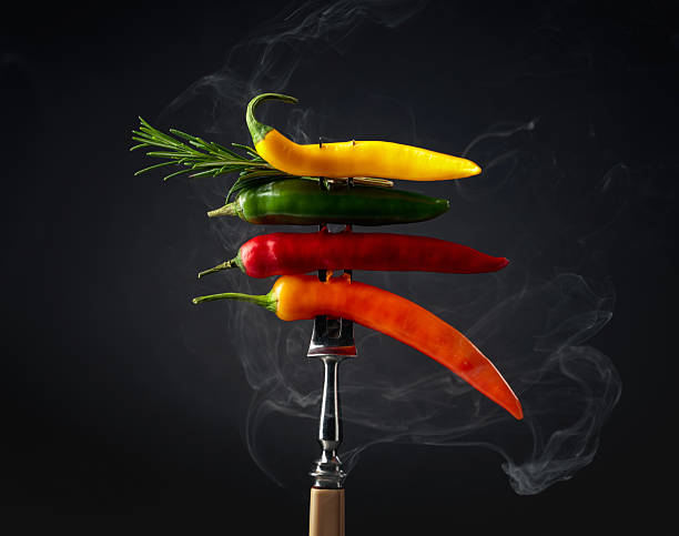 Hot chili peppers with rosemary on black background. Concept of spicy food.