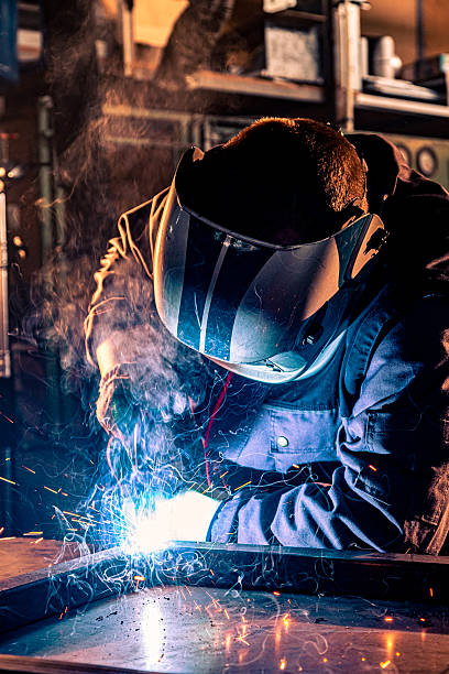 istock Industrial worker welding metal in workshop creating sparks and smoke 2238242153