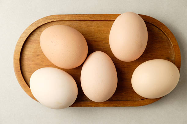 Fresh brown eggs arranged on a wooden platter in a cozy kitchen setting