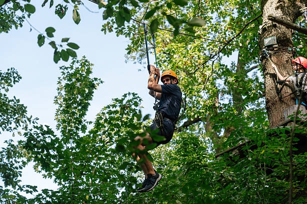 istock Man riding zipline through green forest in adventure park 2238248419