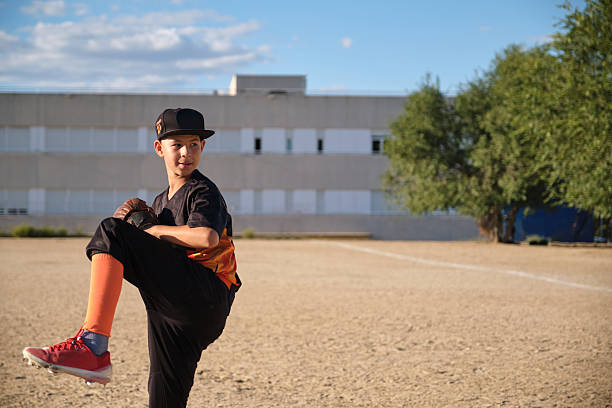 Boy preparing to throw a baseball on a dirt field during an outdoor game