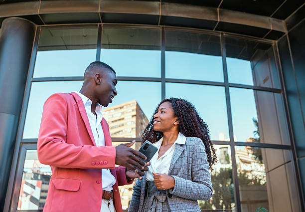 istock Two diverse businesspeople discussing a project using a mobile phone outside office 2238248885