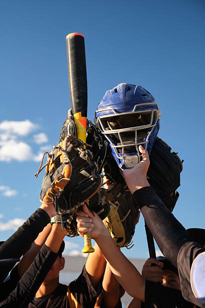 Baseball players holding up equipment, celebrating a game or showing team unity