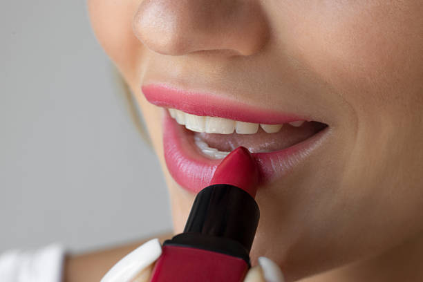 istock Woman putting on lipstick 2238255409