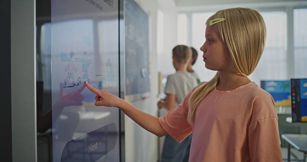 istock Beautiful Schoolgirl Working at Large Digital Screen During Lesson in Bright, Modern Classroom 2238260155