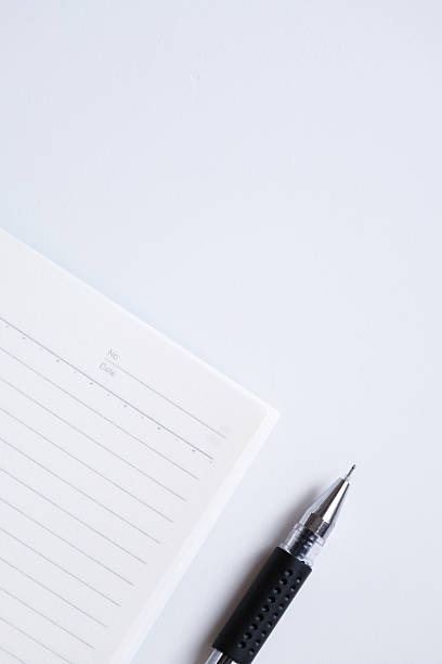 Close-up of blank notebook and pen isolated on white background