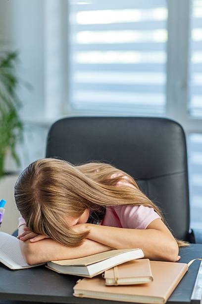 istock Overwhelmed girl collapsed on school desk 2238266419