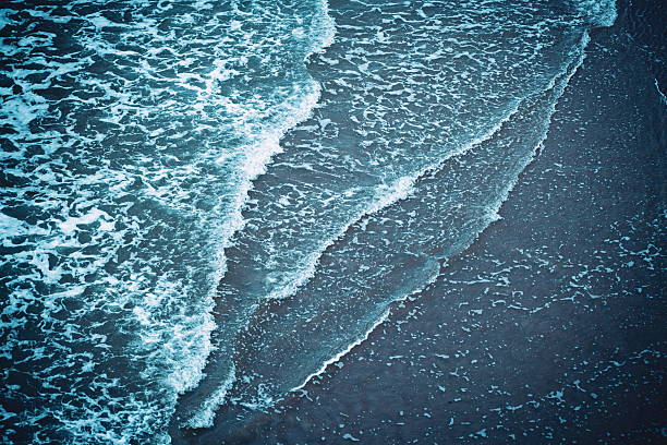 istock Foamy, shallow, tidal waves reaching the sandy shore. Top down view, shallow water, aqua blue cold tones, no people 2238268193