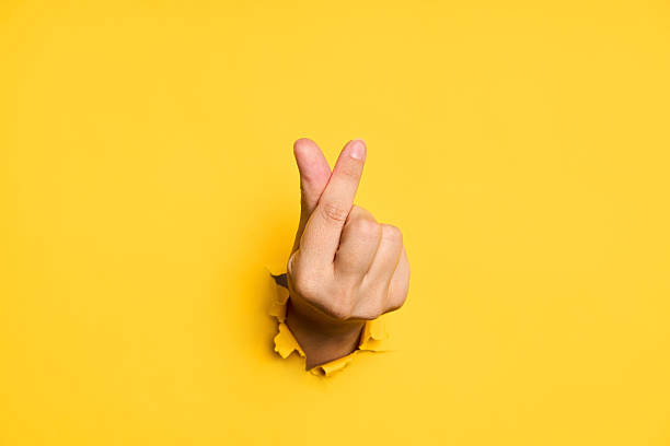 istock Love finger gesture through hole in torn yellow paper 2238271559