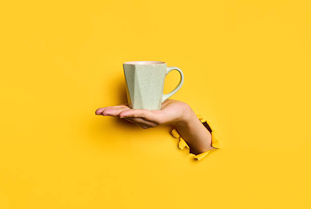 istock Female hand holding cup on yellow background 2238271569