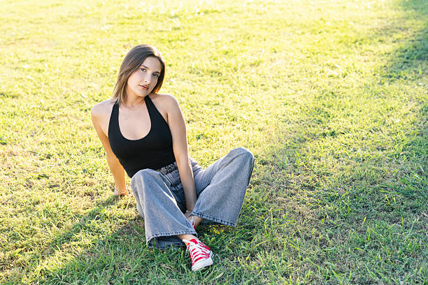 Woman sitting on a grass overlooking the mountains at sunset.