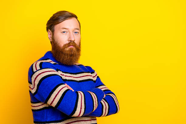 istock Confident bearded man in casual striped sweater posing against a bright yellow background expressing self assurance 2238272178
