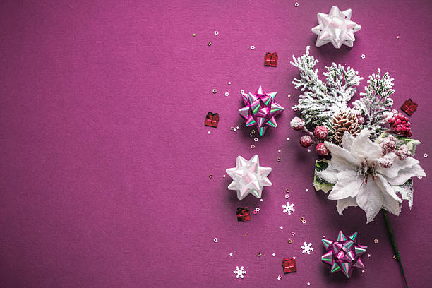Elegant Christmas flat lay composition with ribbons, glitter snowflakes, frosted pine branches, Christmas flower, snowflakes and stars confetti, tinsel on dark violet background. Winter holidays greeting card design. Xmas banner template