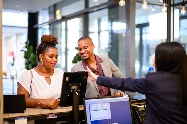 istock Happy business partners checking in at hotel reception with friendly receptionist behind digital tablet 2238272879