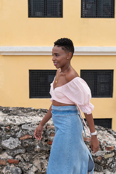 istock Confident black woman walking past yellow building wall 2238276126