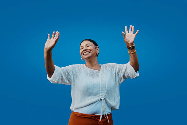istock Joyful African Woman Expressing Authenticity Smiling With Hands Raised On Blue Background 2238277347