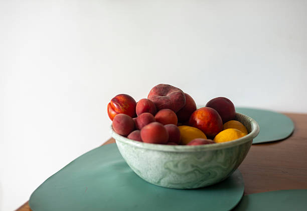 Peaches nectarines plums in marbled green bowl white background
