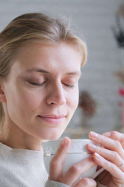 istock young millennial woman holding a hot steaming tea cup looking out a window 2238283494