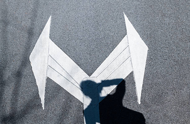 Two directional arrow symbol on asphalt road with people shadow