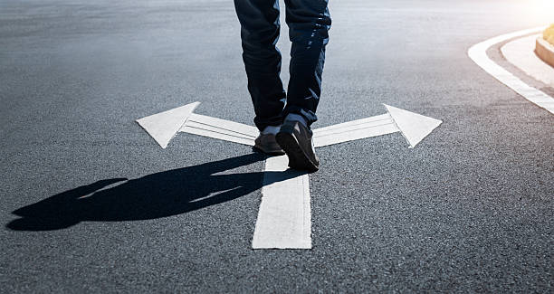 istock Man walking on road with two direction arrow and get to decision which way to go 2238291025