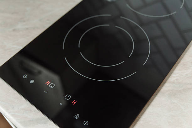 istock A modern black induction cooktop with circular heating elements and control buttons. The surface is sleek and shiny, set against a light-colored countertop. 2238292029
