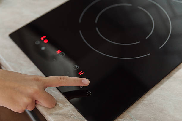 istock Finger pressing control panel on black electric stove with red hot burner active, kitchen appliance, cooking safety concept. 2238292039