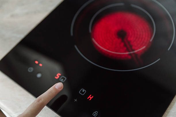 istock Finger pressing control panel on black electric stove with red hot burner active, kitchen appliance, cooking safety concept. 2238292044