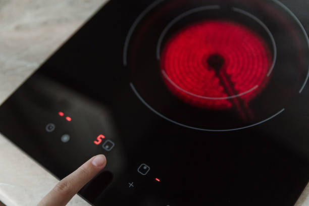 istock Finger pressing control panel on black electric stove with red hot burner active, kitchen appliance, cooking safety concept. 2238292061