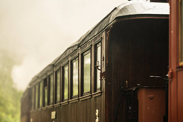Vintage wooden passenger train car with smoke.