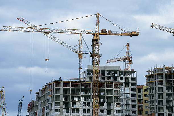 istock Multiple tower cranes working on a large construction site, building new residential high-rise buildings, representing urban development and growth against a cloudy sky 2238296029