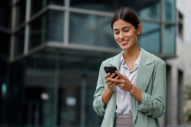 istock Businesswoman smiling outdoors, connecting on smartphone, checking messages, working remotely in a modern city 2238298206