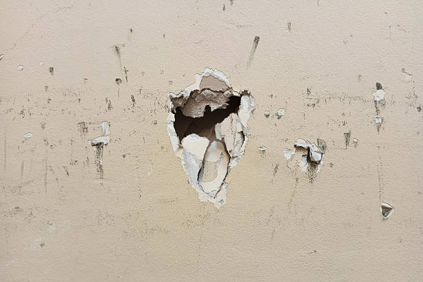istock Holes, scratches, and dirt in a painted plasterboard wall. Background: beige. 2238298546