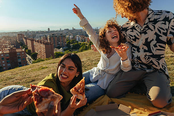Friends eating pizza outdoors in Barcelona during a picnic