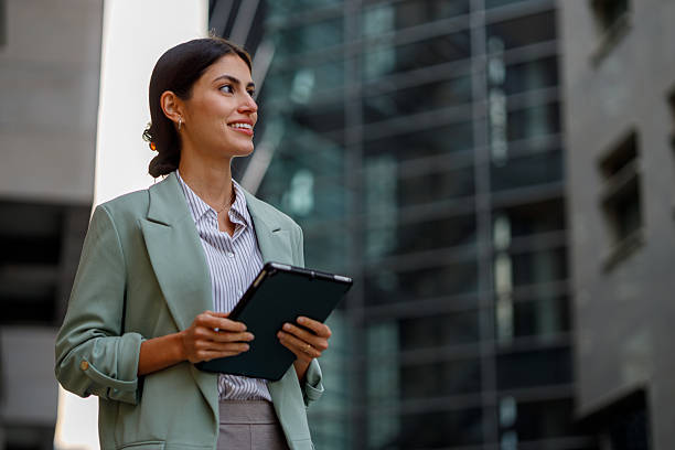 istock Businesswoman standing outdoors with digital tablet looking forward, contemplating future career development and success 2238299565