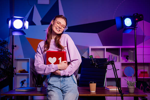 Professional young female blogger holding a tablet in a lit studio office setup with microphone and creative decor
