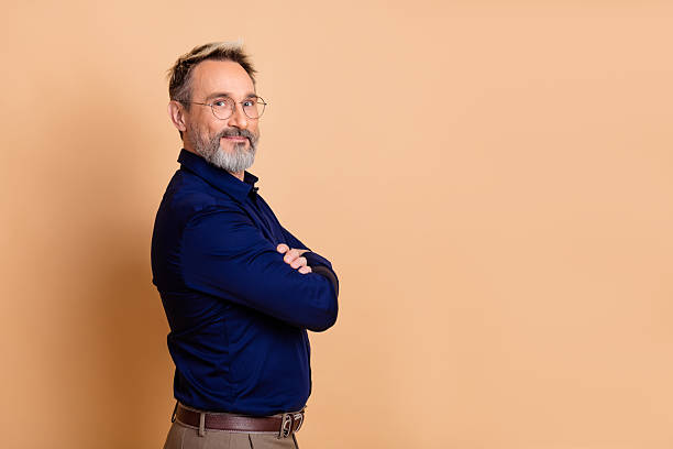 istock Professional middle-aged man in formal attire posing against a beige background, showcasing elegance and style 2238300350