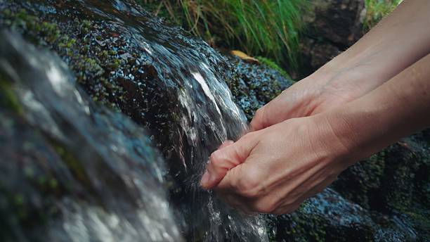 istock Female hiker pauses by the waterfall scooping water in her hands 2238304376
