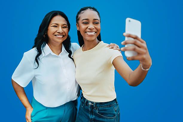 istock Joyful diverse women smiling happily while taking a selfie together on blue background 2238307249