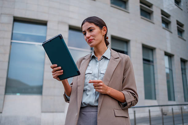istock Businesswoman standing outdoors holding digital tablet while pointing, showing technology innovation and smart working 2238315205
