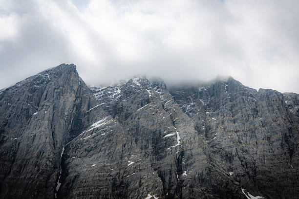 Towering mountain peaks partially shrouded in cloud cover, revealing rugged textures