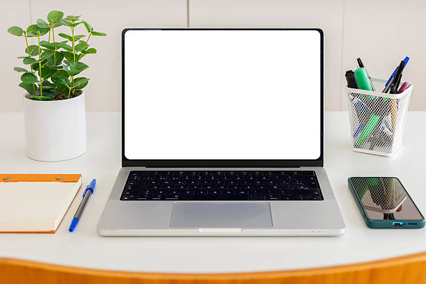 Open laptop with a bright blank screen, notebook, pen, smartphone, and plant on a clean white workspace