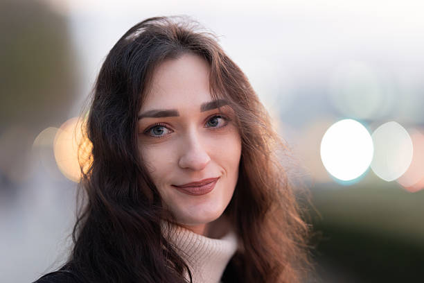 istock Young woman smiling with bokeh lights background 2238327740