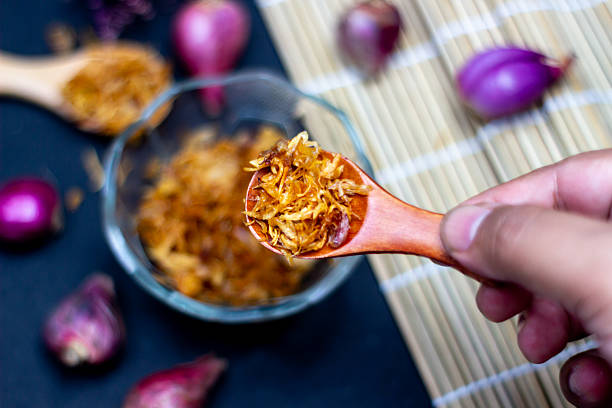 Close up of crispy fried shallots ingredient topping with a bowl and shallots on the table. Perfect for adding flavor to any dish.