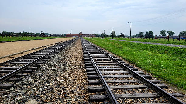 Auschwitz, Poland on photo August 20, 2022, The photograph shows two parallel lines of railway tracks stretching into the distance, leading directly to the main entrance of the camp.