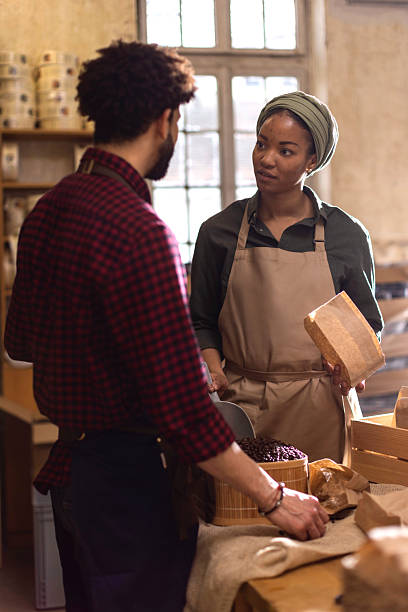 istock Two People Working Behind a Rustic Bakery Counter with Cheese and Grains in a Warm Store Setting 2238334192