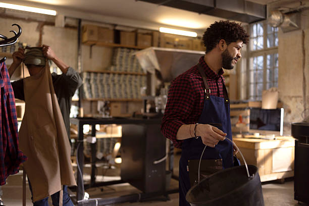 istock Craftsman in Blue Apron Working in Warm Industrial Workshop With Bucket and Tools 2238334421