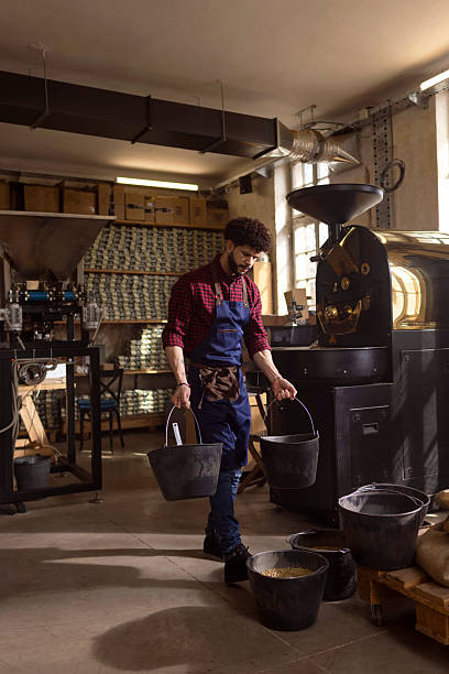 istock Worker In A Roastery Carrying Buckets Of Coffee Beans During Roasting Process 2238334441