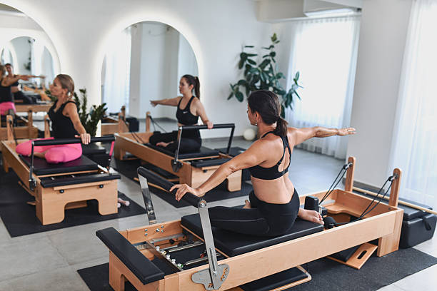 istock Women Engaged In Pilates Reformer Stretching Session In Light Filled Studio 2238335655