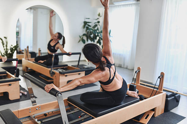 istock Female Athletes Doing Pilates Reformer Stretching Routine In Modern Bright Studio 2238335732
